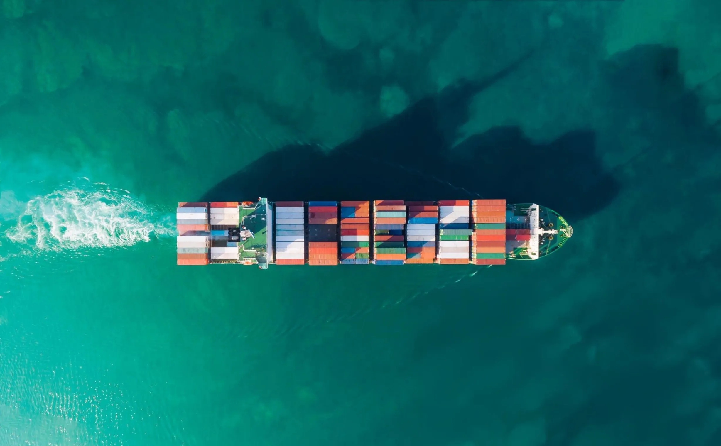 A loaded container ship at sea, seen from above