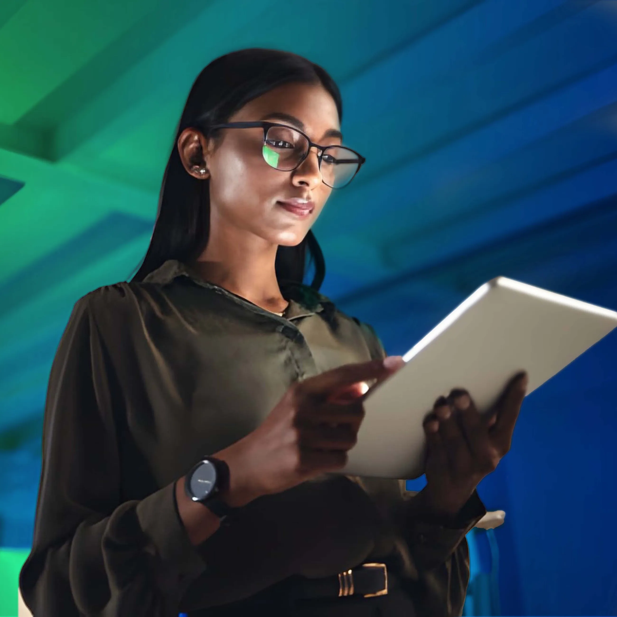 A woman in glasses works on a tablet under blue and green light