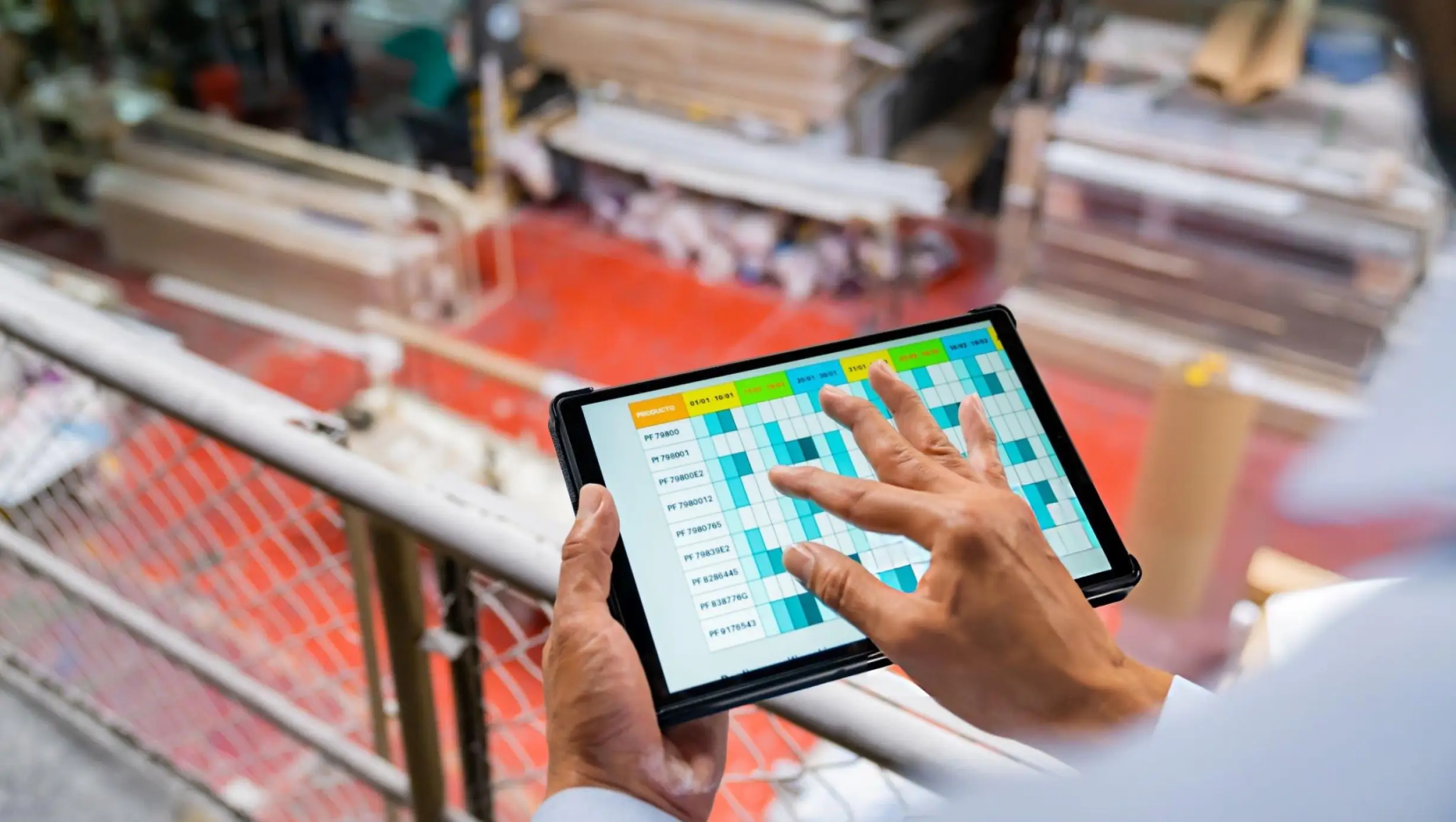 A manager reviews a production schedule on a tablet on the factory floor